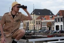 Man in safarikleding en verrekijker in de bebouwde kom